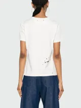 Remera de algodón color blanco con estampa de texto en el frente y manchas negras.