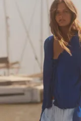 Chaqueta azul de punto con manga larga, volantes en el escote y en los puños, y cierre frontal con lazada.