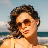 Lentes de sol Sunski modelo Baia Honey Sepia, con montura redonda color dorado y patillas color miel. Lentes polarizados color marrón degradado.