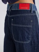 Pantalón ancho de denim con diseño patchwork en diferentes tonos de azul, con tiro alto, corte holgado y cierre frontal con botones.