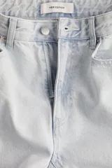 Pantalón jean celeste de denim de algodón rígido, corte ajustado de cintura a muslo y acampanado de rodilla a bajo, con cinco bolsillos, cierre y botón.