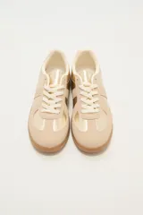 Zapatillas deportivas color beige y dorado con suela marrón.