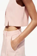 Chaleco color rosa pálido de cuello redondo y sisa. Bajo con aberturas delanteras y cierre frontal con botones.