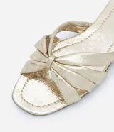 Sandalia plana mule metalizada con puntera cuadrada y tiras cruzadas con efecto crepitante.