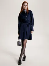 Vestido corto tipo camisa color azul marino, con cuello camisero, cierre frontal con botones y cinturón de lazo.