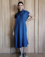 Vestido camisero midi de denim azul, con cuello clásico, manga corta, abotonadura frontal y tajo lateral.