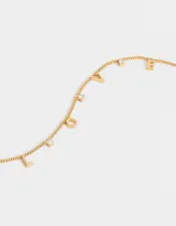 Collar corto dorado con cadena fina y dijes con las letras que forman la palabra 'love' y strass.