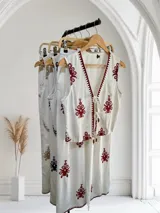 Conjunto de pantalón y chaleco blancos con bordados rojos. El chaleco es corto, con escote en V y se ata en el frente. El pantalón es recto y de tiro alto.