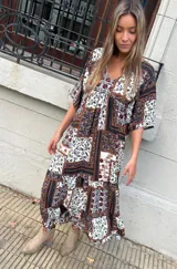 Vestido largo con estampado floral en tonos marrones, blancos y negros. Tiene escote en V, mangas cortas y corte holgado.