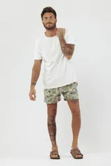 Short de baño con estampado de hojas de palmera en tonos beige, verde y naranja.