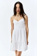 Vestido corto blanco de popelina de algodón, con breteles finos que se atan en moño, escote corazón y falda acampanada con volado en el ruedo.