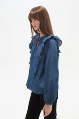 Blusa blanca de calce holgado con cuello en V y lazo frontal. Presenta detalles de volados en el pecho y cuello, y mangas largas con puños elásticos.