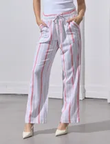 Pantalón de lino a rayas verticales color beige y blanco, con pretina ancha elastizada, lazo de ajuste y bolsillos inclinados.