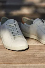 Zapatillas Ecco Leisure de cuero blanco con perforaciones laterales y detalle en cuero color beige en el talón.