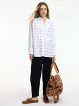 Camisa blanca de algodón con cuello camisero, cierre frontal con botones y tachas plateadas en el frente.