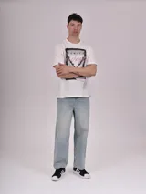 Remera manga corta color crudo con estampa rectangular con foto de calle con palmeras y texto en color fucsia.