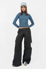 Pantalón deportivo gris de nylon, de calce recto y tiro medio, con elástico en la cintura, cordones ajustables y detalle de recorte con vivo a contratono en los laterales.