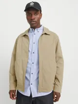 Sobrecamisa shacket color beige con cierre de cremallera y diseño resistente. Confeccionada en tejido liviano, delgado y transpirable de poliéster reciclado. Presenta cuello clásico, mangas largas con puños abotonados, cierre con cremallera y bolsillos frontales funcionales.