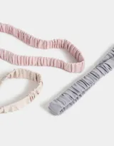 Set de tres vinchas elásticas deportivas, una color lila, una color negro y una color beige.