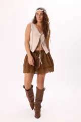 Minifalda color crema con bordado calado tipo broderie, cintura elastizada con cordón ajustable y detalle de cuentas de madera. Diseño de doble capa con volados.