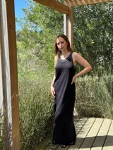 Vestido largo negro de tejido de punto, corte recto y breteles finos con ribete blanco.