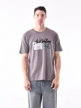 Remera gris con estampado frontal de texto y diseño abstracto.