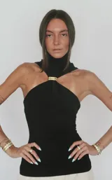 Top blanco sin mangas con cuello halter y detalle de anillo metálico en el centro.