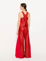 Pantalón de cuero vacuno negro, de silueta amplia con recortes diagonales en delantero y espalda. Tiene un complemento de lino al tono aplicado en los laterales.