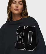 Suéter oversize de algodón orgánico color azul marino, con cuello redondo y puños y ruedo acanalados. Presenta un gran parche con el número "10" en el pecho, con borde blanco y textura afelpada, y la inscripción "10DAYS" verticalmente en el número 1.