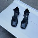 Zapato de cuero vacuno color negro con textura croco, con talón cubierto, pulsera con hebilla y taco de madera forrado en cuero.