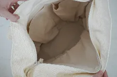 Bolso tote de lona color crudo con asas de hombro. Decorado con parches bordados de motivos playeros y pañuelo rojo estampado atado a una de las asas.