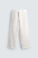 Pantalón de corte relajado confeccionado en tejido de lino color beige claro. Cuenta con cintura elástica, bolsillos frontales, bolsillos traseros de plastrón y cierre frontal con cremallera y botón.