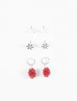 Set de tres pares de aros plateados: un par de aros tipo botón con forma de media luna, un par de aros tipo botón con forma de flor y cristales verdes, y un par de aros colgantes con forma de racimo de uvas rojas.