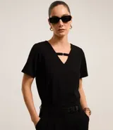 Blusa negra de crepé con cuello en V y mangas cortas. El cuello posee una tira horizontal unida por una pequeña hebilla metalizada.