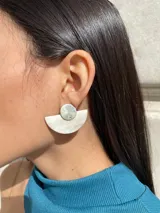 Aros colgantes con forma geométrica, hechos con guampa y detalles metálicos dorados o plateados.
