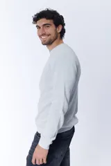 Buzo de tejido de punto con textura de gofre o waffle, color gris melange claro, de cuello redondo y manga larga.