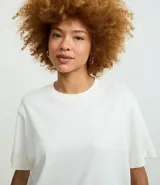 Remera gris de corte cuadrado, cuello redondo y mangas cortas.