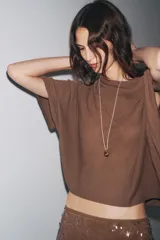 Top color crema de tejido de punto, con cuello asimétrico y mangas anchas.