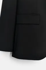 Blazer negro de lana con cuello solapa de muesca, manga larga con hombreras y botones, bolsillos delanteros con solapa y bolsillo de vivo en el pecho.