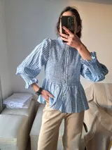 Camisa celeste y blanca a cuadros con cuello mao, mangas largas abullonadas con puños elásticos y peplum.