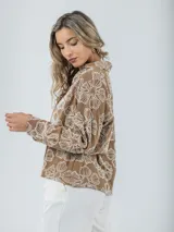 Blusa color crudo con bordados florales, cuello camisero y mangas largas.