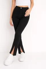 Pantalón jean negro de tiro alto, corte flare con aberturas en los tobillos y costuras frontales decorativas.