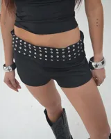Short negro de tiro alto con cintura ancha adornada con ojales metálicos.