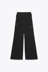 Pantalón negro de tiro alto con cintura elástica ajustable con cordones laterales, forro interior corto y pernera ancha.