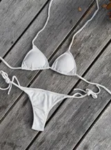 Conjunto de bikini azul con corpiño de triángulos movibles con almohadillas desmontables, que se ata al cuello y a la espalda. La bombacha es vedetina con tiritas a los costados para atar a medida de la cadera.