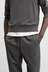 Pantalón negro de corte cropped, con cintura elástica ajustable con cordón, bolsillos laterales y traseros de vivo. El bajo tiene terminación con vuelta.