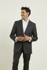 Traje de poliéster negro, corte regular fit, compuesto por saco con solapa de muesca, cierre de dos botones, bolsillos con solapa y pantalón de vestir con bolsillos laterales y traseros.