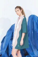 Vestido corto tipo túnica con cuello camisero, manga corta y cierre frontal con botones. Diseño con bloques de color verde, blanco y beige en patrón ondulado.