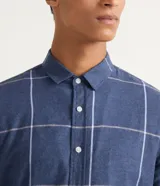 Camisa de franela azul con estampado de cuadros blancos y beige, de manga larga y cuello camisero.