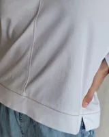 Remera blanca de mangas largas con cuello en V y costuras a la vista.